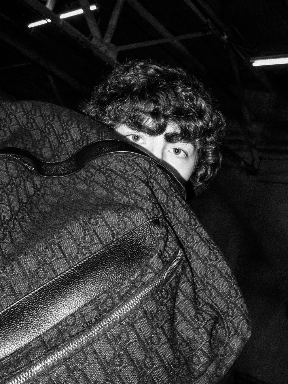 Black and white portrait peeking over a backpack