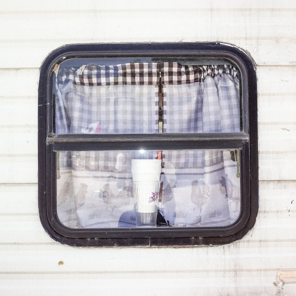 Shine cup in a trailer window with gingham curtains